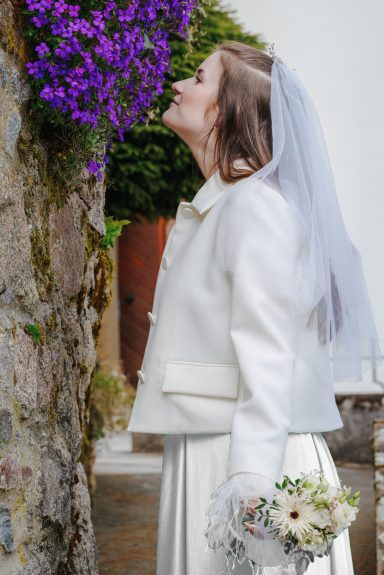 Blüte der Liebe Frau in weißem Brautkleid lächelt, während sie eine blühende Pflanze betrachtet.