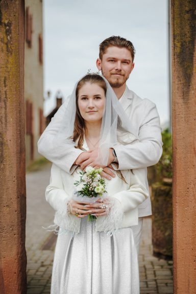 Unter den Bögen der Liebe Hochzeitspaar in eleganter Trauung, umgeben von historischen Säulen.